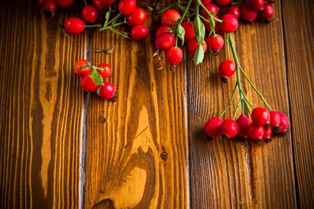 ripe red dogrose in a basket on a wooden tableの写真素材