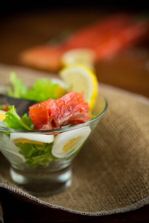 lettuce salad with salted salmon, boiled eggs on a wooden table.の写真素材