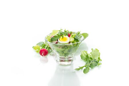 Spring salad with arugula, boiled eggs, fresh radish, salad leaves in a glass bowlの写真素材