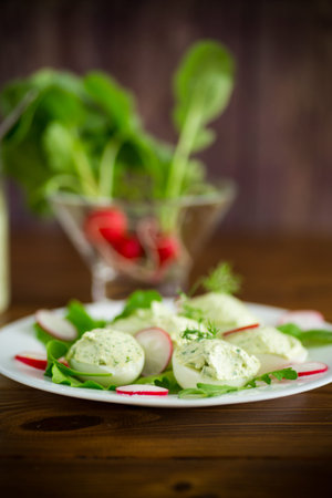 Boiled stuffed eggs with green cheese filling with arugula leaves and radish