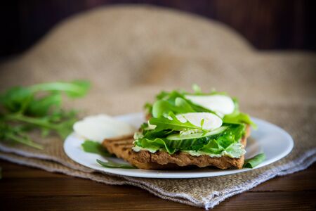 fried bread toasts with salad leaves, cheese spread and mozzarella in a plate on a wooden tableの写真素材