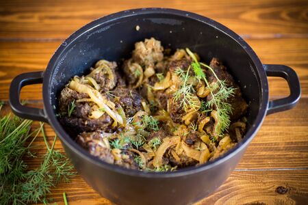 fried liver with onions and dill in a black panの写真素材