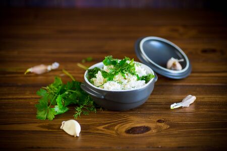 salted homemade cottage cheese with garlic and herbs in a bowl on a wooden tableの写真素材