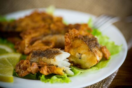 fried hake fish in batter with lettuce and lemon in a plateの写真素材