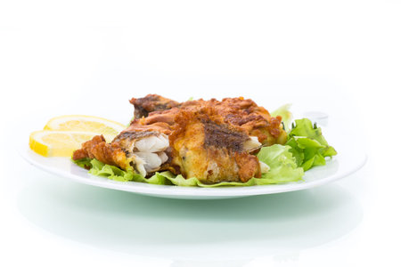 fried hake fish in batter with lettuce and lemon in a plate