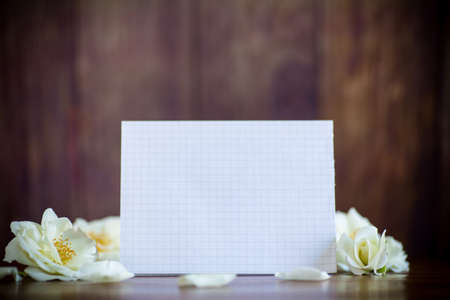 bouquet of beautiful white roses and blank card on a wooden tableの写真素材