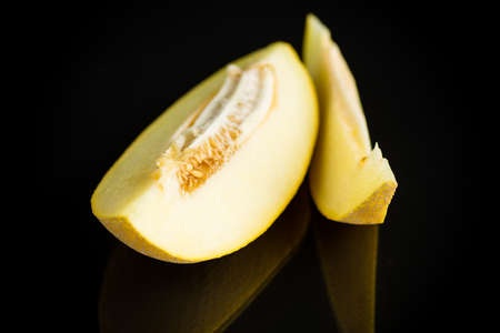 Studio shot of notched ripe melon galia with slice isolated on black backgroundの写真素材