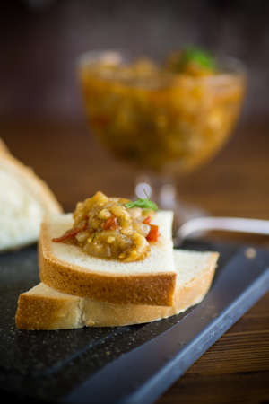 cooked eggplant caviar with spices and bread on a wooden tableの写真素材