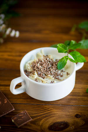 sweet noodles with milk and grated chocolate in a bowl on a wooden tableの写真素材