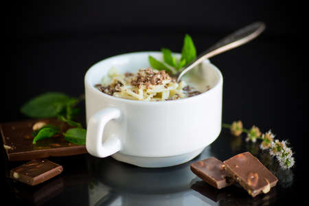 sweet noodles with milk and grated chocolate in a bowl on a black backgroundの写真素材