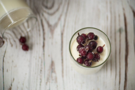 Homemade sweet yogurt with frozen berries in a glass on the tableの写真素材