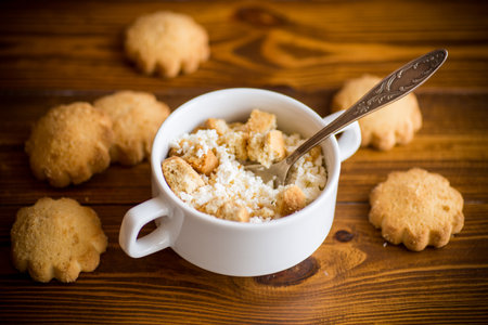 Homemade cottage cheese with pieces of shortbread cookies for breakfast, on a wooden tableの写真素材
