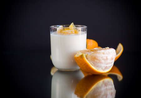 homemade sweet yogurt in a glass with oranges isolated on black backgroundの写真素材