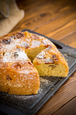 cooked sweet biscuit with dried apricots and nuts inside on a wooden table