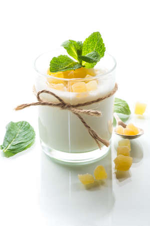 Sweet homemade yogurt with candied fruits in a glass isolated on white backgroundの写真素材
