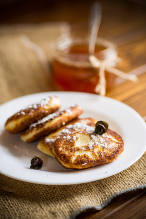 sweet fried cottage cheese pancakes in a plate on a wooden table