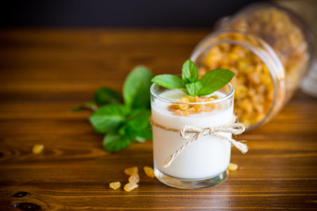 sweet homemade yogurt with raisins in a glass on a wooden tableの写真素材