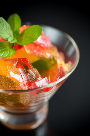 colored sweet fruit jelly in glass glass isolated on black background