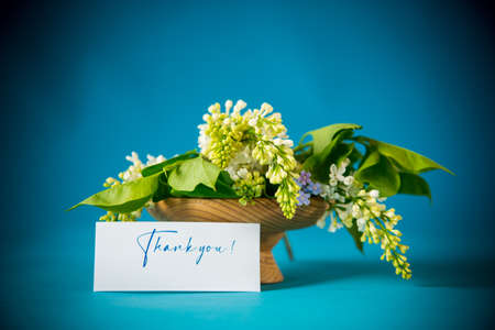 bouquet of white lilacs with greeting card on blue backgroundの写真素材
