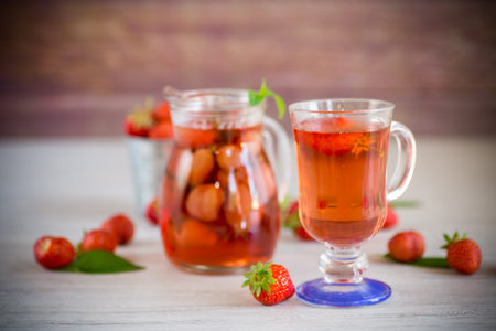 Sweet refreshing berry compote of ripe strawberries in a decanter on a wooden table