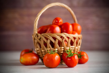 fresh ripe red tomatoes in a basket on a wooden tableの写真素材