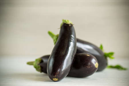 raw fresh ripe eggplants on a light wooden tableの写真素材