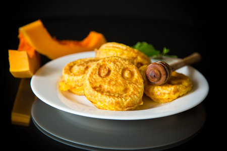 sweet lush pumpkin pancakes with honey in a plate on a black backgroundの写真素材