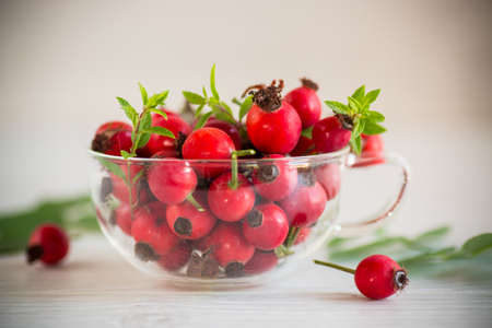 a bunch of ripe red rose hips on a wooden tableの写真素材