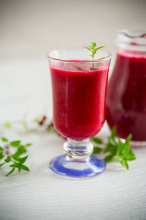 freshly squeezed thick natural juice with pulp from ripe red viburnum in a decanter on a wooden tableの写真素材