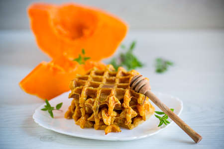 sweet baked pumpkin waffles with honey in a plate on a wooden tableの写真素材