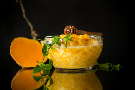sweet boiled pumpkin porridge in a bowl with honey isolated on black backgroundの写真素材