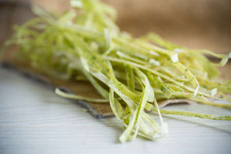 homemade dried green raw noodles with herbs on a wooden tableの写真素材