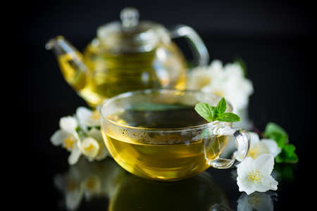 Composition with cup of jasmine tea and flowers isolated on black backgroundの写真素材