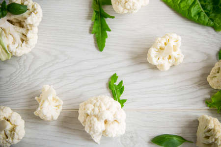 inflorescences of small raw cauliflower on a light wooden tableの写真素材