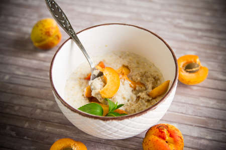 Healthy breakfast of boiled oatmeal with fresh apricots in a bowl on the table.の写真素材