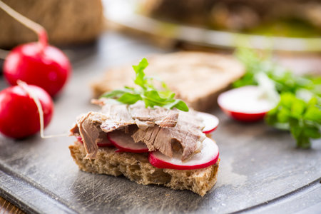 sandwich with baked meat, radish and herbs on a wooden table.の写真素材