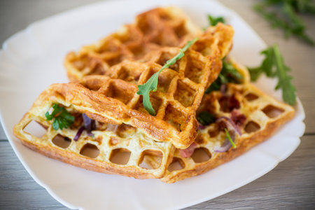 Egg omelette stuffed with onions and herbs, fried in the form of waffles, on a wooden tableの写真素材