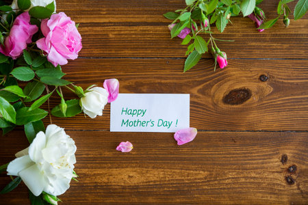 Floral background of pink and white roses on a dark wooden table