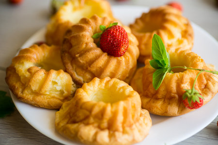 Cooked sweet curd cupcakes with fresh strawberries and mint on a wooden table.の写真素材