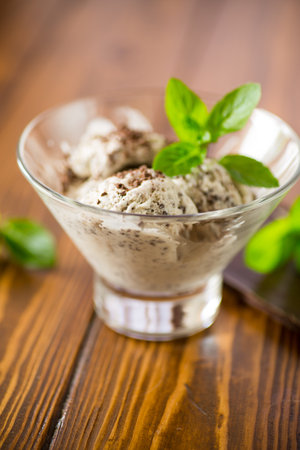 homemade ice cream with pieces of grated dark chocolate, in a bowl on a wooden table.の写真素材