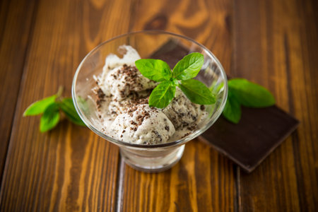 homemade ice cream with pieces of grated dark chocolate, in a bowl on a wooden table.の写真素材