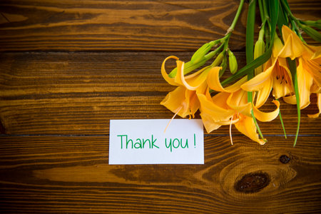 bouquet of beautiful yellow lilies on a dark wooden tableの写真素材