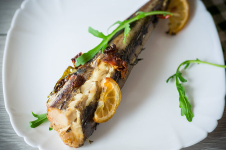 Baked fish with seasonings and spices in a plate on a wooden table