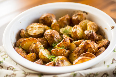potatoes baked with sesame seeds, herbs and spices in the oven in a ceramic form.