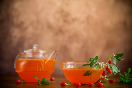 Prepared drink from ripe goji berries in a glass cup and teapot, on a wooden table.の写真素材