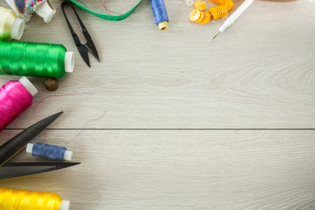 a set of tools and threads for sewing clothes, on a wooden background.