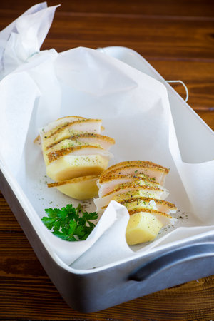 Raw potatoes stuffed with lard and spices, prepared for baking in baking paper.の写真素材