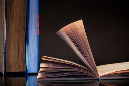 open book for reading and a stack of books, isolated on a black background.の写真素材