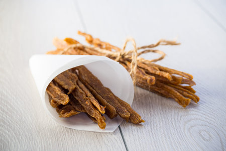 A handful of dried chicken meat, marinated with spices, on a light wooden table. Beer spicy snack.