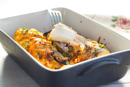 fish baked with spices and vegetables in the oven in a ceramic dish.